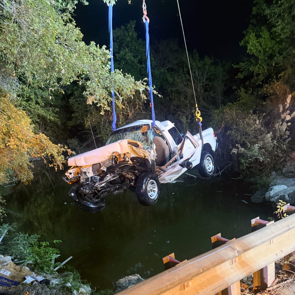 a tow truck recovering a pickup truck from a river.